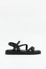 Sandalias negras de símil cuero con agarre ajustable de velcro en el talón, tiras trenzadas y plataforma de 3cm de alto.