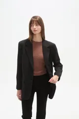 Blazer negro de poliéster, de corte holgado, con cuello solapa y cierre de un botón. Incluye dos bolsillos frontales con solapa y un bolsillo superior simulado.