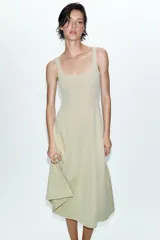 Vestido midi de color beige con escote cuadrado y tirantes anchos. Presenta un diseño entallado en el torso con costuras verticales marcadas y una falda con caída evasé.