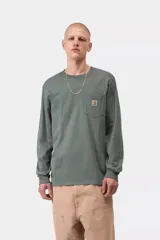 Remera Carhartt de manga larga en color verde militar, con cuello redondo, corte recto y un bolsillo parche en el pecho que incluye una etiqueta con el logo de la marca.