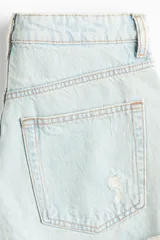 Short denim de cinco bolsillos confeccionado en algodón rígido, con diseño de tiro súper alto, detalles de roturas y desgastes, cierre frontal con botón y terminaciones deshilachadas.