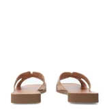 Sandalias tipo slide de cuero color beige, con tiras anchas y detalle metálico dorado en el empeine. Presentan una base plana con punta cuadrada.