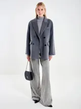 Chaqueta de paño gris de corte amplio, con solapas clásicas, cierre frontal cruzado de botones y bolsillos laterales con solapa.