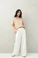 Sweater de tejido de punto color blanco hueso, con cuello redondo y mangas acampanadas. Presenta una hilera de botones a tono en el lateral de cada manga.