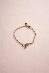 Pulsera de cadena dorada con dijes de piedras naturales y cuentas de colores. Presenta un diseño delicado con eslabones finos y cierre de mosquetón.