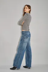 Jean de tiro medio con diseño de doble cintura superpuesta y pierna recta. Confeccionado en denim azul oscuro, presenta cierre y botón metálico, con costuras verticales decorativas en el frente.