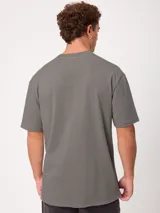 Remera holgada de algodón color beige con lavado ácido, cuello redondo ancho y diseño de tres pequeños círculos estampados en el pecho.