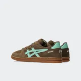 Championes Asics modelo Skyhand OG, de diseño retro inspirado en el balonmano de los años 90. Confeccionados en gamuza color marrón con detalles en verde menta en los laterales y el talón, cuentan con suela de goma color caramelo y amortiguación de EVA en el talón.