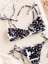 Conjunto de bikini con estampado floral en tonos azul y blanco. El corpiño es tipo triángulo con lazo en el centro y breteles finos ajustables. La bombacha es de corte clásico.