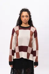 Buzo de tejido de punto con diseño geométrico de cuadros en tonos marrones, beige y bordó. Presenta cuello redondo, puños y borde inferior en color negro, con mangas largas y corte holgado.