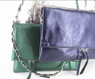 Cartera plateada tipo bandolera con solapa y cierre magnético. Tiene una cadena corta y una cadena larga.