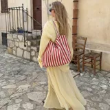 Cartera tipo tote bag confeccionada en tela resistente, con diseño de rayas verticales en tonos rojo y blanco, y asas dobles de hombro.