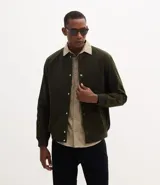 Campera bomber de terciopelo con cuello redondo, cierre frontal con botones forrados, bolsillos laterales y puños y cintura elásticos.