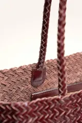 Cartera tote de cuero vacuno trenzado a mano, color bordó, de diseño espacioso con asas firmes.
