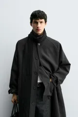 Trench de corte oversized confeccionado en tejido compacto con mezcla de lana. Presenta cuello solapa, cierre frontal con botonadura, mangas largas y bolsillos de vivo en la cadera.