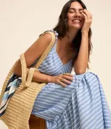 Vestido midi de tricolina a rayas verticales celestes y blancas, con breteles finos con nudo, escote en pico y falda con volantes.