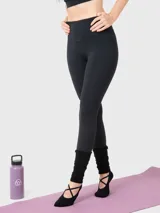 Calza deportiva de tiro alto y largo al tobillo, confeccionada en tejido técnico elástico de color negro. Presenta un diseño liso sin bolsillos, ideal para actividades físicas.