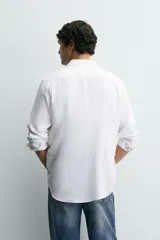 Camisa blanca de lino de corte regular fit, con cuello abotonado, manga larga y cierre frontal de botones.