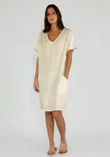 Vestido corto color beige de lino y algodón, con escote en V y mangas cortas.