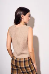 Chaleco de punto sin mangas, color camel jaspeado, con escote en V y cierre frontal de tres botones marrones.