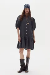 Vestido corto de lino color gris oscuro, con mangas abullonadas, cierre frontal con botones y volado en el ruedo.