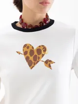 Remera de jersey pesado color blanco, con cuello redondo en contraste negro y estampa central de un corazón con diseño animal print atravesado por una flecha.