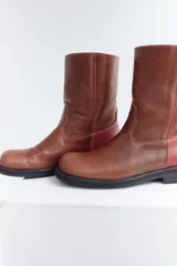 Botas cortas de cuero color marrón con detalle de costuras en la parte delantera y trasera. La parte trasera es de cuero color bordó.