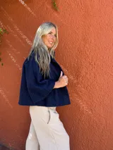 Capa corta de tejido de bucle en color azul, con corte en A, mangas raglán y cierre frontal con tres botones grandes.