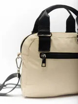 Bolso pequeño color beige con diseño acolchado, doble asa de mano negra y correa larga negra desmontable y regulable.