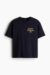 Remera boxy de algodón color negro, con cuello redondo acanalado, mangas cortas y hombros caídos. Presenta un pequeño estampado amarillo en el pecho con el texto "sports archives 08".