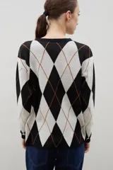 Buzo de punto con diseño de rombos en tonos azul y marrón, con cuello redondo y mangas largas.