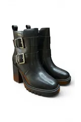 Bota alta de cuero negro con plataforma track, taco ancho y dos tiras con hebillas metálicas plateadas en el lateral.