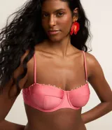 Top de bikini rosa de media taza con aro y tirantes finos ajustables. Cuenta con detalles de pequeños adornos de madera en el borde superior y cierre trasero.