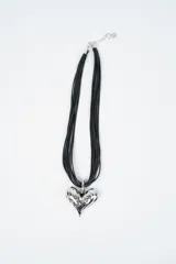 Collar compuesto por múltiples hilos negros finos y un dije central en forma de corazón con acabado metálico plateado de textura irregular.