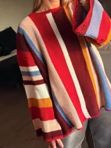 Sweater de punto tejido a mano con diseño de rayas verticales multicolores. Presenta silueta oversize, cuello a la base, mangas largas acampanadas y terminaciones en crochet en los bordes.
