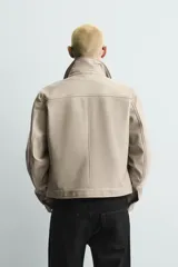 Chaquetas de corte cropped y efecto vinilo en color negro, con cuello solapa, manga larga con puño abotonado y cierre frontal con broches a presión.