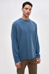 Remera de manga larga color beige, confeccionada en algodón lavado con textura suave. Presenta cuello redondo con detalle de costura en V, corte clásico y estampado pequeño en el pecho con la palabra Uniform.