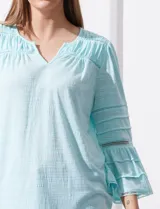 Blusa color celeste con escote en V, mangas largas acampanadas con detalle de crochet y frunces en los hombros.