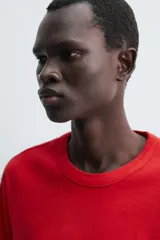 Camiseta de corte relajado confeccionada en tejido de algodón compacto. Presenta cuello redondo con acabado de rib doble y mangas cortas. Su apariencia única es resultado de un proceso especial de tintado y acabado.