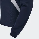 Chaqueta deportiva con capucha y cierre frontal, color azul marino, con patrón geométrico en relieve en el cuerpo. Presenta detalles en blanco en los laterales y puños y tobillos ajustados. Lleva el logo de Macron y el escudo de Uruguay Rugby en el pecho.