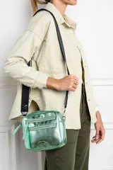 Cartera bandolera rectangular color oro viejo, con textura granulada y correa ancha de tela negra regulable. Tiene dos bolsillos frontales con cierre y un bolsillo interno.