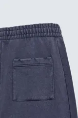 Pantalón jogger de corte wide fit confeccionado en algodón con interior de rizo. Presenta cintura elástica ajustable con cordón, bolsillos laterales y un bolsillo trasero de plastrón. Cuenta con un efecto lavado y acabados irregulares en el ruedo.