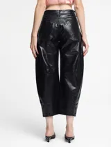 Pantalón de silueta globo confeccionado en cuero sintético con acabado efecto vintage. Presenta un corte de pierna ancha, cintura con cierre y botón, y costuras horizontales a la altura de la rodilla.