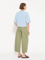 Pantalón de corte relajado color verde oliva, confeccionado en algodón. Presenta un diseño de cinco bolsillos estilo jeanero, tiro alto, pierna ancha y largo al tobillo.