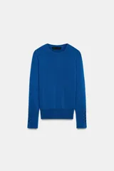 Sweater de punto liso en color azul, con cuello redondo y manga larga terminada en puños con detalles de botones metálicos.