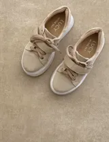 Sneakers de mujer estilo deportivo y urbano, color negro con detalles en beige claro. Presentan puntera y talón en negro, cuerpo principal en negro, y estrella lateral, cordones y tira de velcro en beige claro. La suela es blanca y el interior negro con la inscripción "LUCY IN THE SKY".