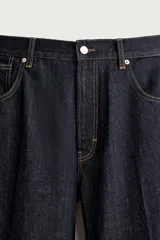 Pantalón jean azul marino oscuro de corte recto y holgado, largo cropped, tiro medio y tejido rígido de denim sin lavado. Cuenta con diseño de cinco bolsillos y costuras en tono tabaco contrastante.
