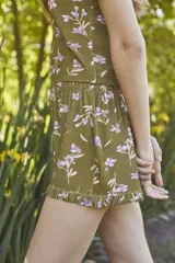 Conjunto de pijama verde oliva con estampado de flores lilas, compuesto por un top de mangas cortas con escote en V y un short con cintura elástica y volados en el ruedo.