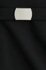 Pollera mini de tiro alto, confeccionada en tela lisa, con cierre lateral oculto y cinturón extraíble con hebilla metálica plateada.