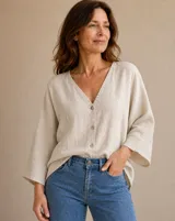 Camisa beige de lino con escote en V, cierre frontal de botones y mangas amplias tres cuartos.